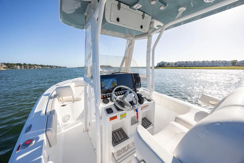 Slide: The Image of 2023 Sea Hunt Ultra 234 boat interior with steering console on a sunny day. - 14