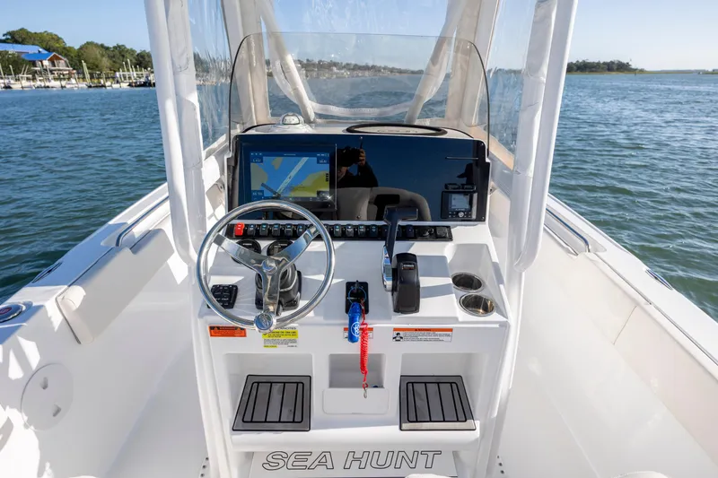 Slide: The Image of 2023 Sea Hunt Ultra 234 boat console with steering wheel and navigation display on water. - 15