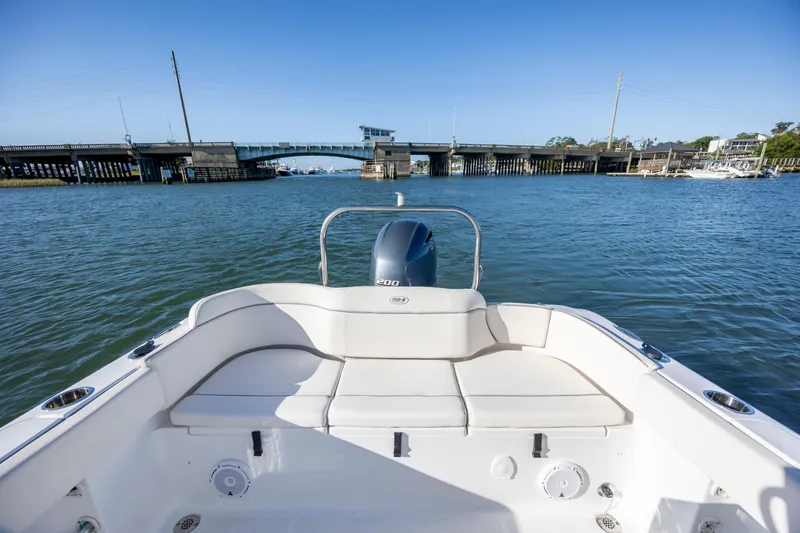 Slide: The Image of 2023 Sea Hunt Ultra 234 boat on water near a bridge, showcasing rear seating and motor. - 19