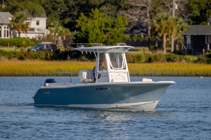 Slide: The Image of 2023 Sea Hunt Ultra 234 boat cruising on a scenic waterway. - 2
