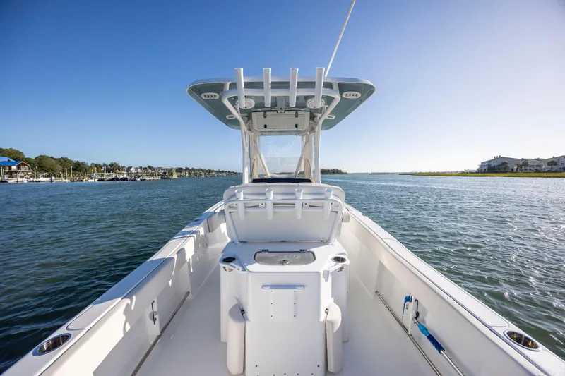 Slide: The Image of 2023 Sea Hunt Ultra 234 boat on calm water under clear blue sky. - 23