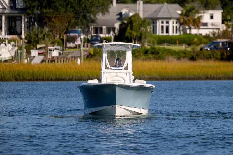 Slide: The Image of 2023 Sea Hunt Ultra 234 boat cruising on a serene waterway near coastal homes. - 3
