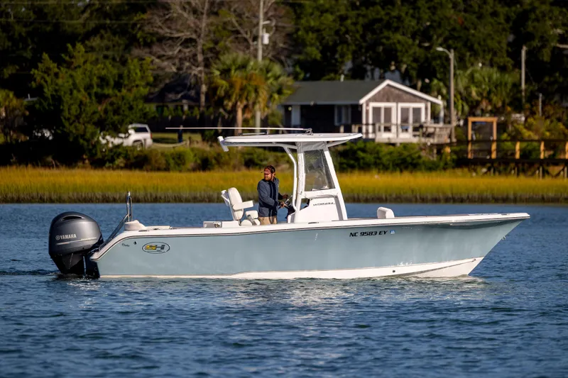 Slide: The Image of 2023 Sea Hunt Ultra 234 boat cruising on a calm lake with scenic background. - 4