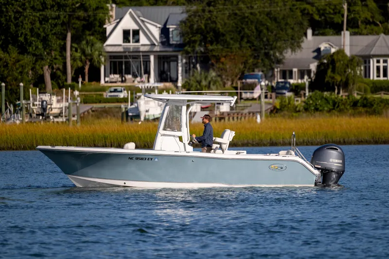 Slide: The Image of 2023 Sea Hunt Ultra 234 boat cruising on a serene waterway near waterfront homes. - 5