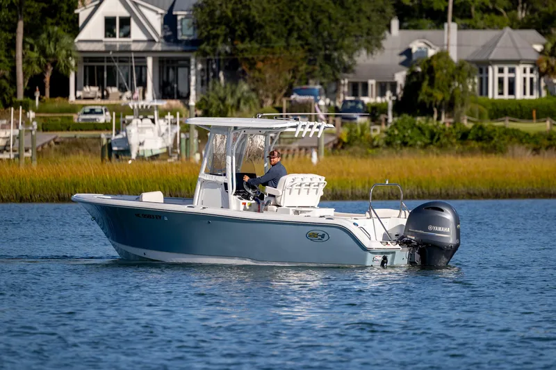 Slide: The Image of 2023 Sea Hunt Ultra 234 boat cruising on a calm river near waterfront homes. - 6