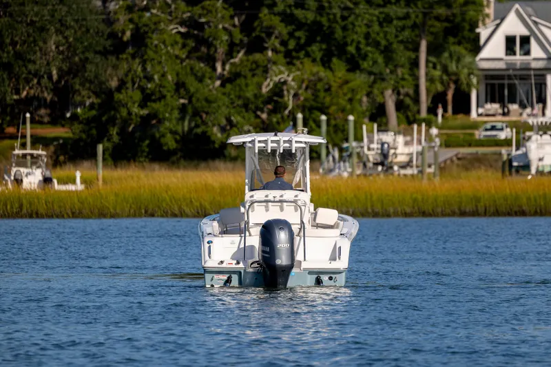 Slide: The Image of 2023 Sea Hunt Ultra 234 boat cruising on a calm river near a marina. - 7