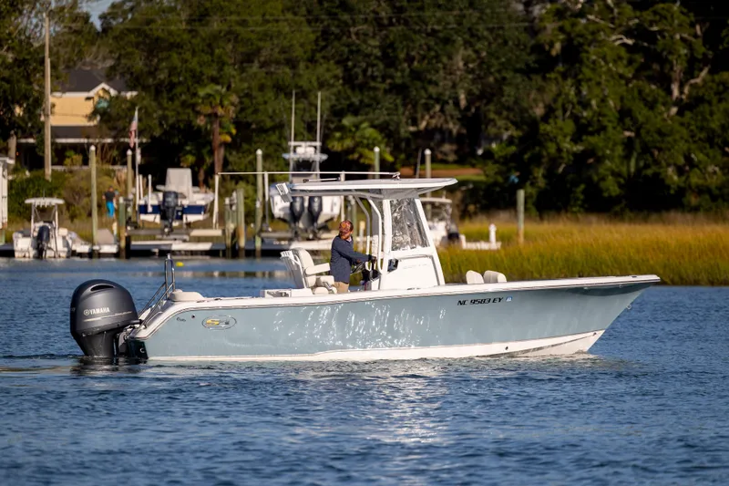 Slide: The Image of 2023 Sea Hunt Ultra 234 boat cruising on a calm waterway with lush greenery. - 8