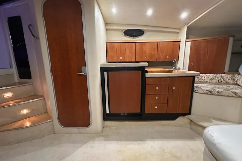 Slide: The Image of 1998 Wellcraft 3200 Martinique interior with wooden cabinetry, compact kitchen, and cozy seating area. - 12