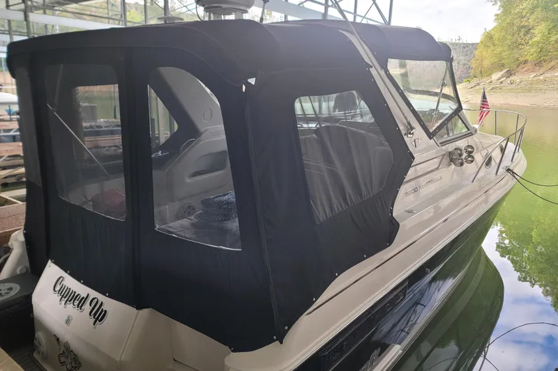 Slide: The Image of 1998 Wellcraft 3200 Martinique boat docked with black canopy and American flag. - 2