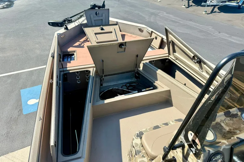 Slide: The Image of 2019 Excel 230 Bay Pro boat interior with open storage compartments and fishing gear. - 13