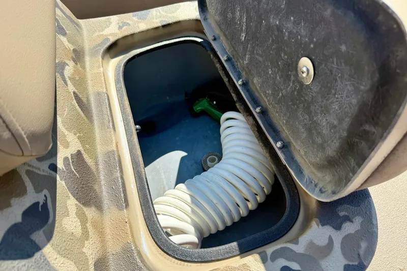 Slide: The Image of Storage compartment in 2019 Excel 230 Bay Pro boat with coiled hose inside. - 24