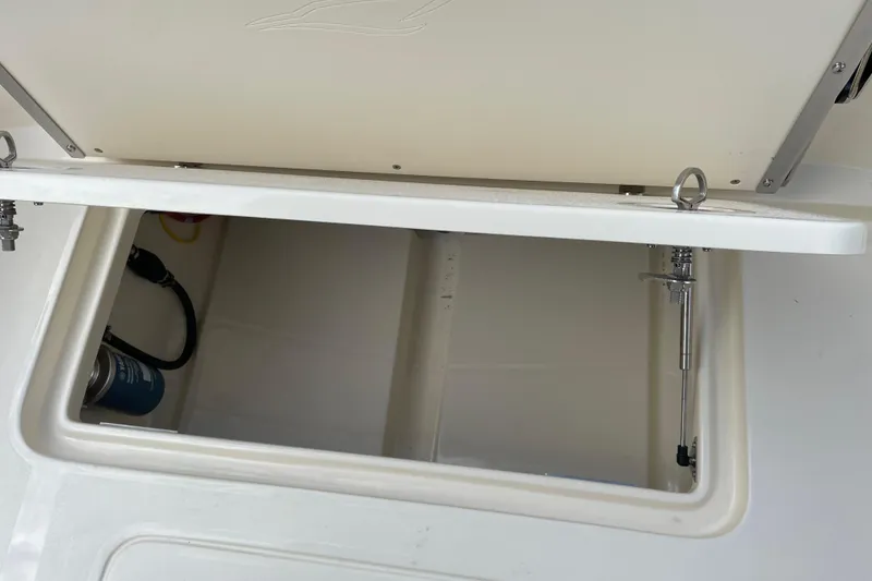 Slide: The Image of Open storage compartment on 2026 Scout 215 XSF boat, showing interior details. - 14