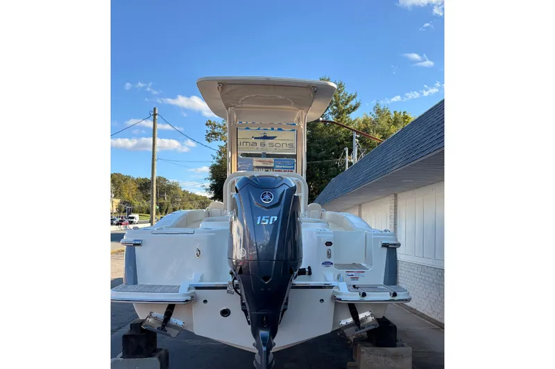 Slide: The Image of 2026 Scout 215 XSF boat with Yamaha 150 engine, parked outdoors under clear sky. - 3