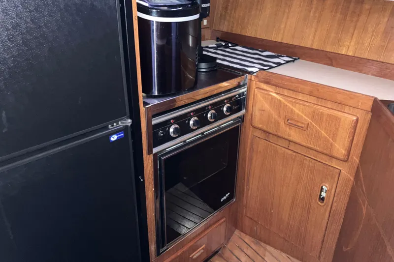 Slide: The Image of 1987 President 37 Sundeck kitchen with stove, fridge, and wooden cabinetry. - 36
