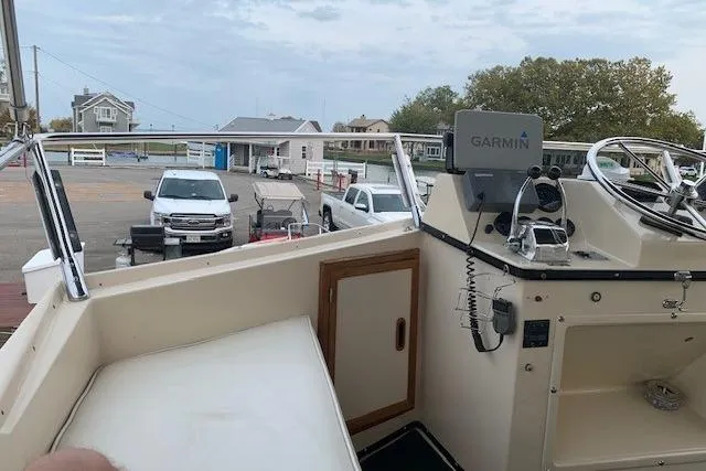 Slide: The Image of 1987 President 37 Sundeck boat helm with Garmin navigation, docked near parked vehicles. - 11