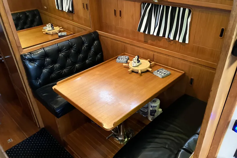Slide: The Image of 1987 President 37 Sundeck interior with wood table, black leather seating, and nautical decor. - 34