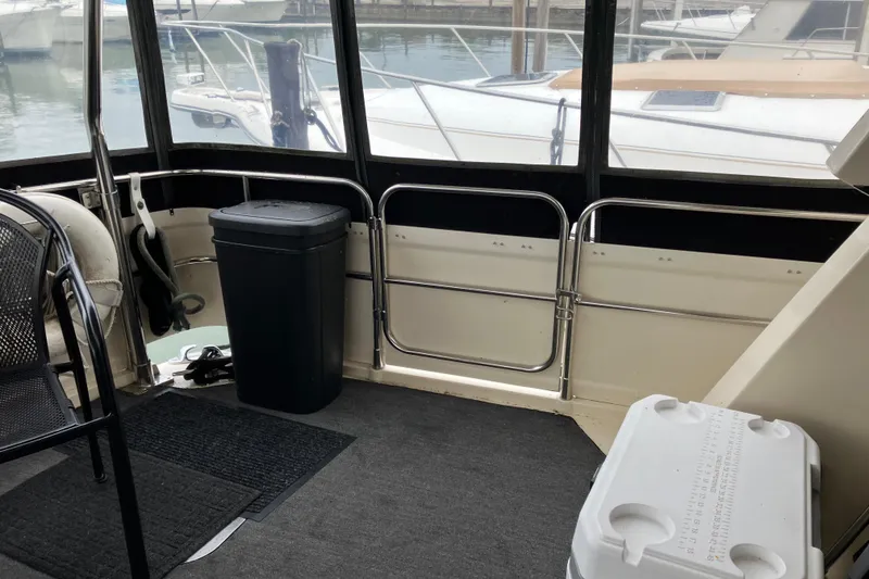 Slide: The Image of 1987 President 37 Sundeck interior with seating, trash bin, and cooler, docked at marina. - 3