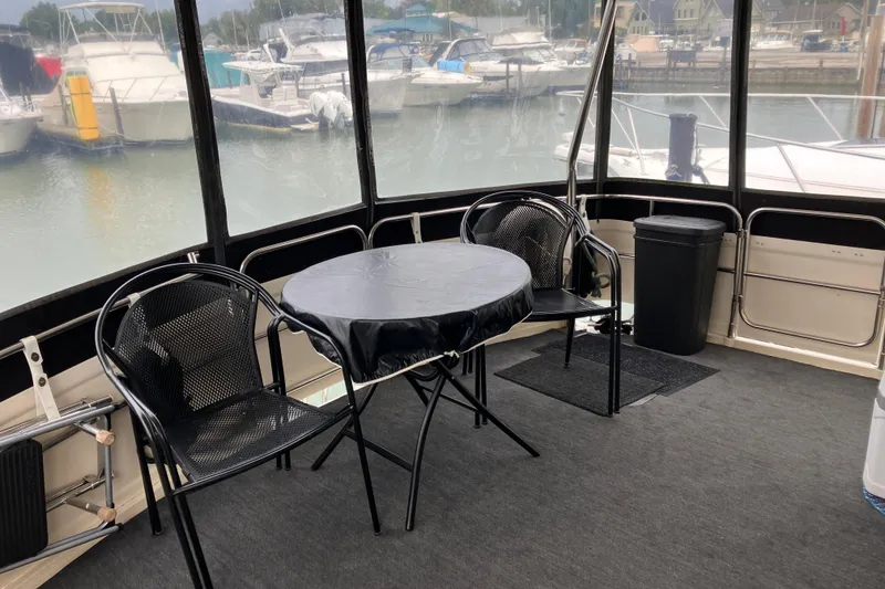 Slide: The Image of 1987 President 37 Sundeck yacht interior with table, chairs, and marina view. - 2