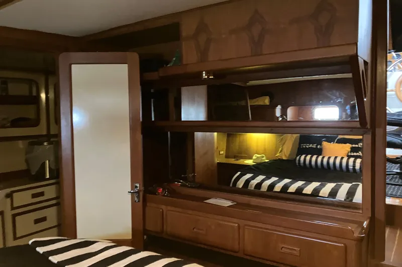 Slide: The Image of Interior of 1987 President 37 Sundeck yacht with cozy wooden cabin and striped bedding. - 47