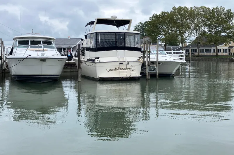 Slide: The Image of 1987 President 37 Sundeck yacht docked between two boats on a calm lake. - 73