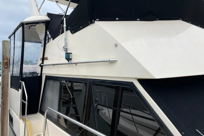 Slide: The Image of 1987 President 37 Sundeck yacht with black canvas cover and railing, docked at marina. - 9
