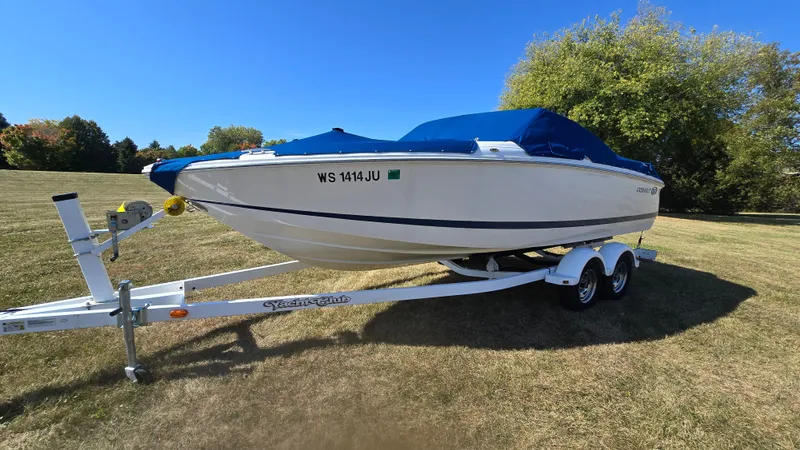 Slide: The Image of 2013 Cobalt 210 boat on trailer, parked on grassy field under clear blue sky. - 1