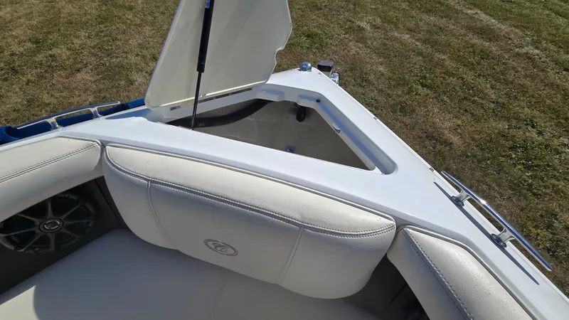 Slide: The Image of 2013 Cobalt 210 boat interior with open storage compartment on grassy area. - 24