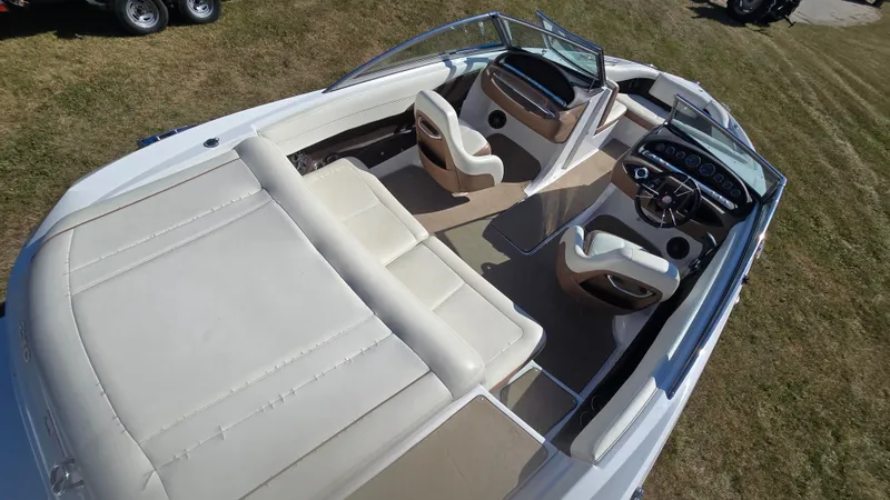 Slide: The Image of 2013 Cobalt 210 boat interior with beige seating and dashboard, viewed from above. - 6