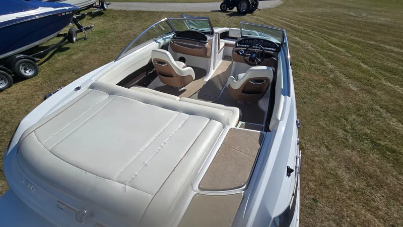 Slide: The Image of 2013 Cobalt 210 boat with beige interior, parked on grass, showcasing seating and dashboard. - 8