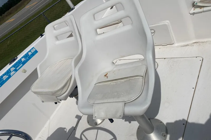 Slide: The Image of 2001 Angler 2100 Center Console boat seats, white and slightly worn, on deck. - 7