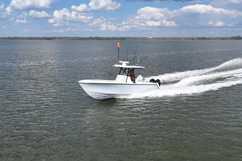 Slide: The Image of 2023 SeaVee 32 boat cruising on open water under a partly cloudy sky. - 48