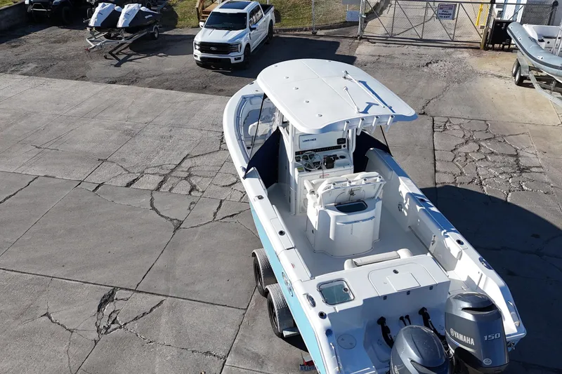 Slide: The Image of 2015 Sea Hunt Gamefish 25 boat on trailer, parked near vehicles and jet skis. - 4