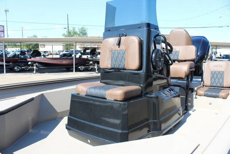 Slide: The Image of 2026 Excel Bay Pro Elite 230 boat interior with brown and black seating, parked at a dealership. - 12