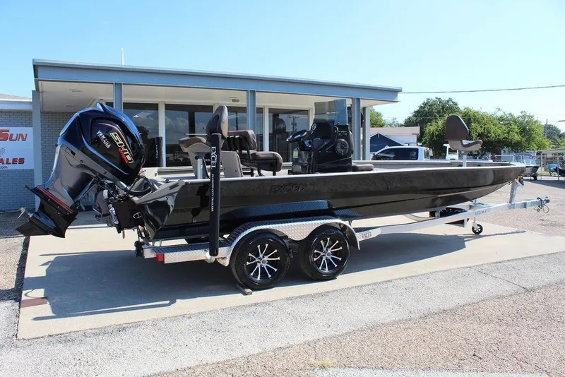 Slide: The Image of 2026 Excel Bay Pro Elite 230 boat on trailer, parked outside dealership. - 2