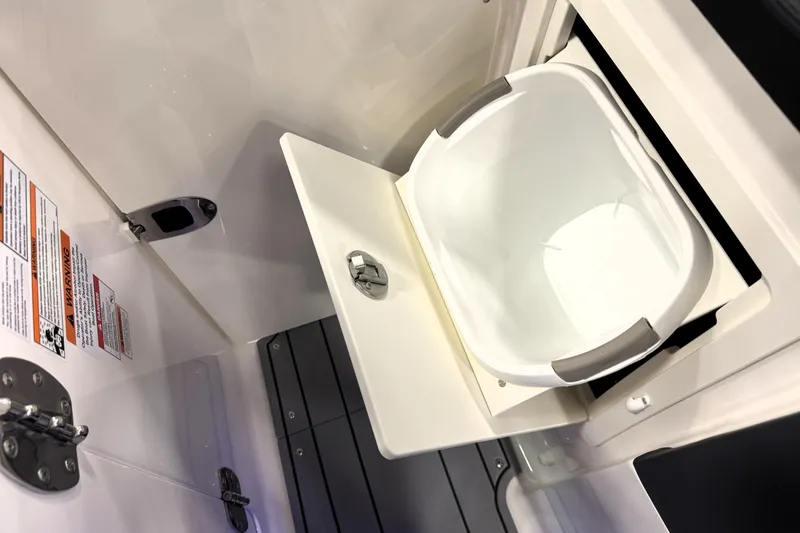 Slide: The Image of 2026 Chaparral GTS 6 boat interior storage compartment with white bucket and safety labels. - 19
