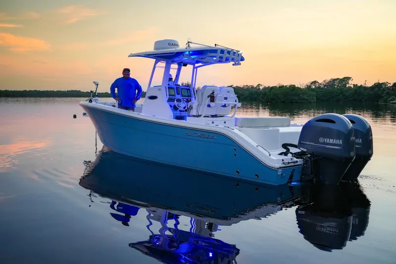 Slide: The Image of 2023 Cobia 262cc boat on calm water at sunset with Yamaha engines. - 10
