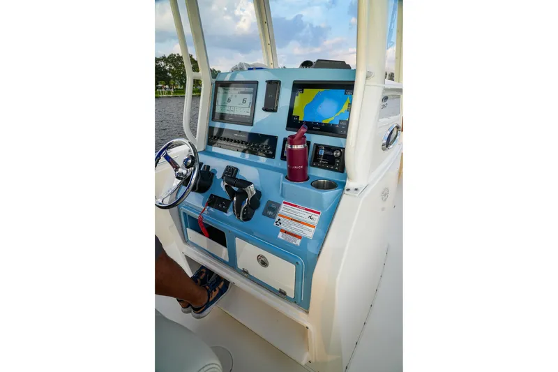 Slide: The Image of 2023 Cobia 262cc boat dashboard with navigation screens and steering wheel. - 5