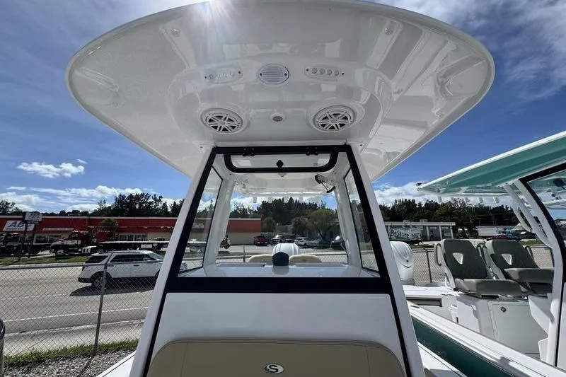Slide: The Image of 2026 Sportsman Masters 247OE Bay Boat with T-top and speakers, parked outdoors. - 5