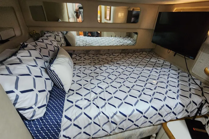 Slide: The Image of Cozy cabin interior of 1995 Sea Ray 450 Sundancer with patterned bedding and wall-mounted TV. - 5