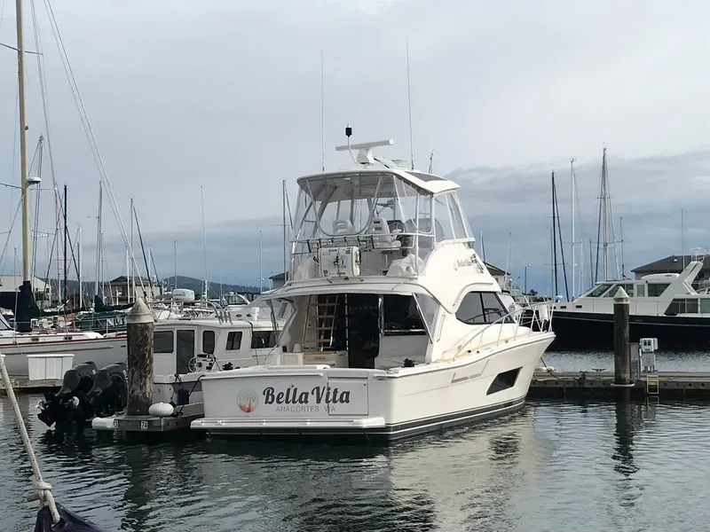 The Image of 2017 Riviera 43 Flybridge yacht on calm water at sunset, city skyline in background. - 0
