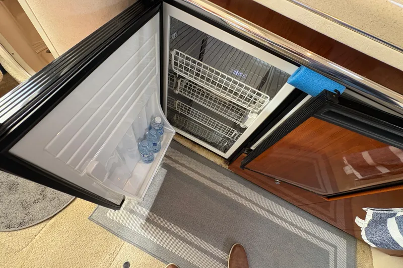 Slide: The Image of Open refrigerator inside 2003 Sea Ray 360 Sundancer yacht, with water bottles and storage baskets. - 46