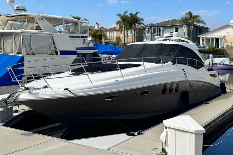 The Image of 2006 Sea Ray 48 Sundancer yacht docked at marina with nearby boats. - 0