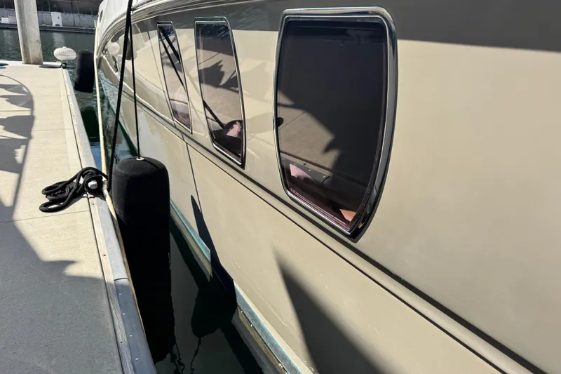 Slide: The Image of 2006 Sea Ray 48 Sundancer yacht docked, showing sleek windows and reflective surface. - 37