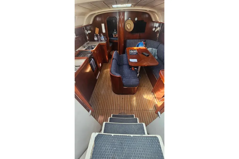 Slide: The Image of Interior of 1996 Beneteau Oceanis 440 sailboat with wooden flooring and cozy seating area. - 16