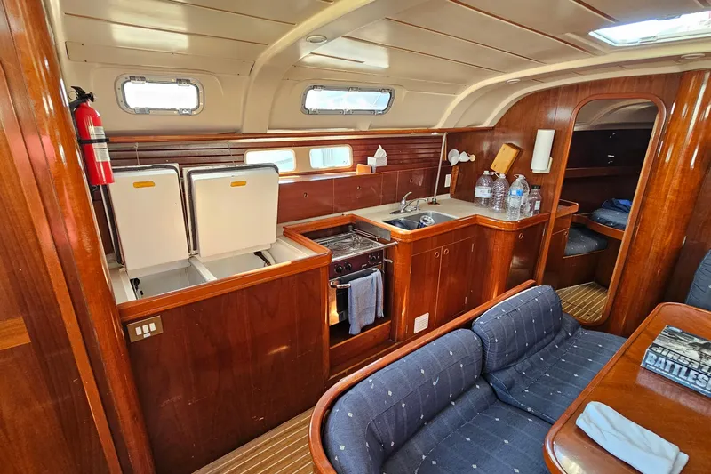 Slide: The Image of Interior of 1996 Beneteau Oceanis 440 yacht with wooden cabinetry and cozy seating area. - 22