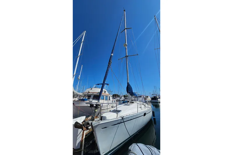 Slide: The Image of Sailboat Beneteau Oceanis 440, 1996 model, docked in a marina under clear blue sky. - 3