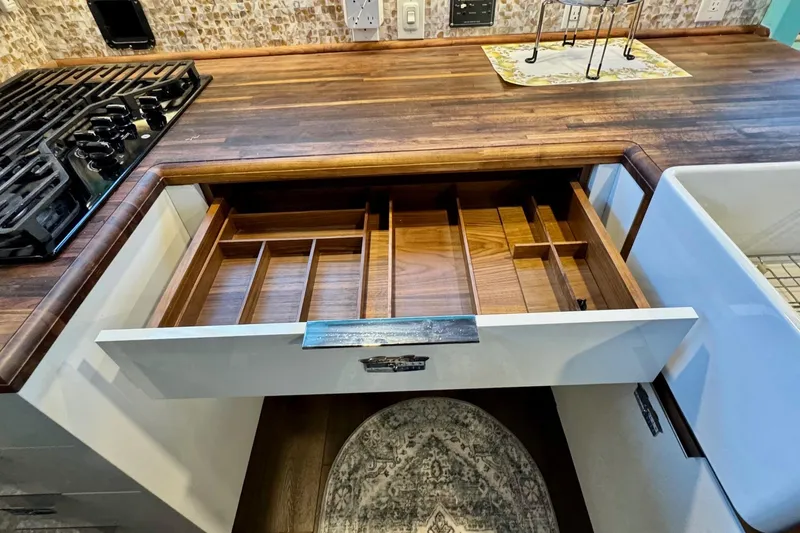 Slide: The Image of Open kitchen drawer with wooden dividers, next to stove and farmhouse sink. - 38