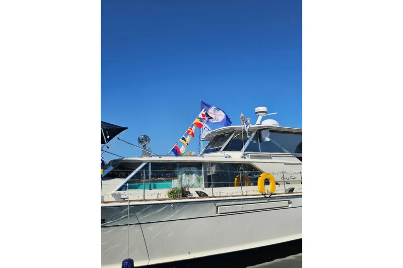Slide: The Image of 1970 Chris-Craft Commander 42 yacht with flags, docked under clear blue sky. - 5