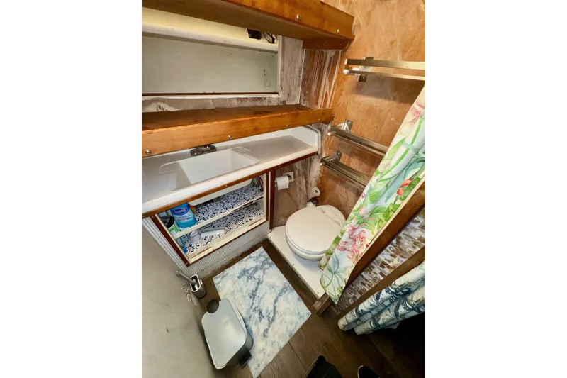 Slide: The Image of 1970 Chris-Craft Commander 42 bathroom with sink, toilet, and floral shower curtain. - 59