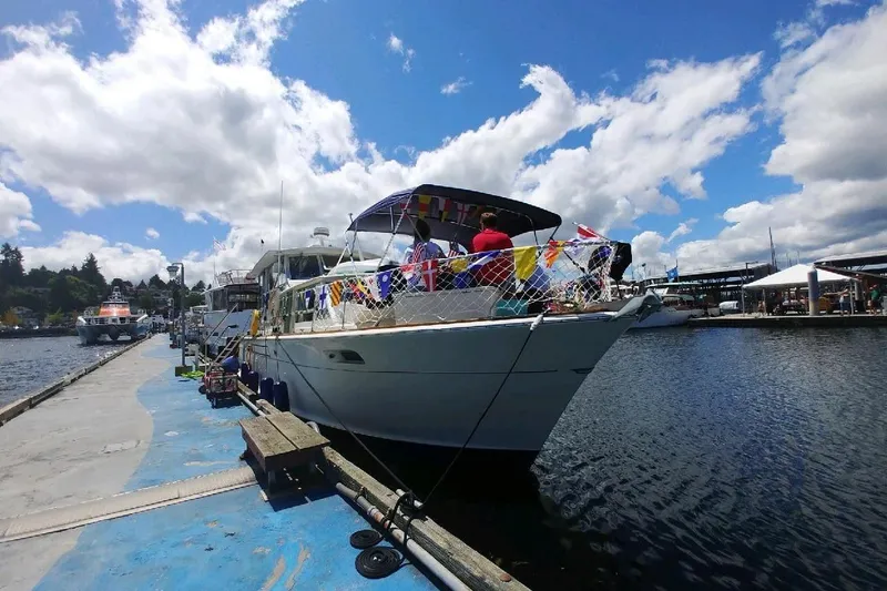 Slide: The Image of 1970 Chris-Craft Commander 42 docked, decorated with colorful flags under a partly cloudy sky. - 9